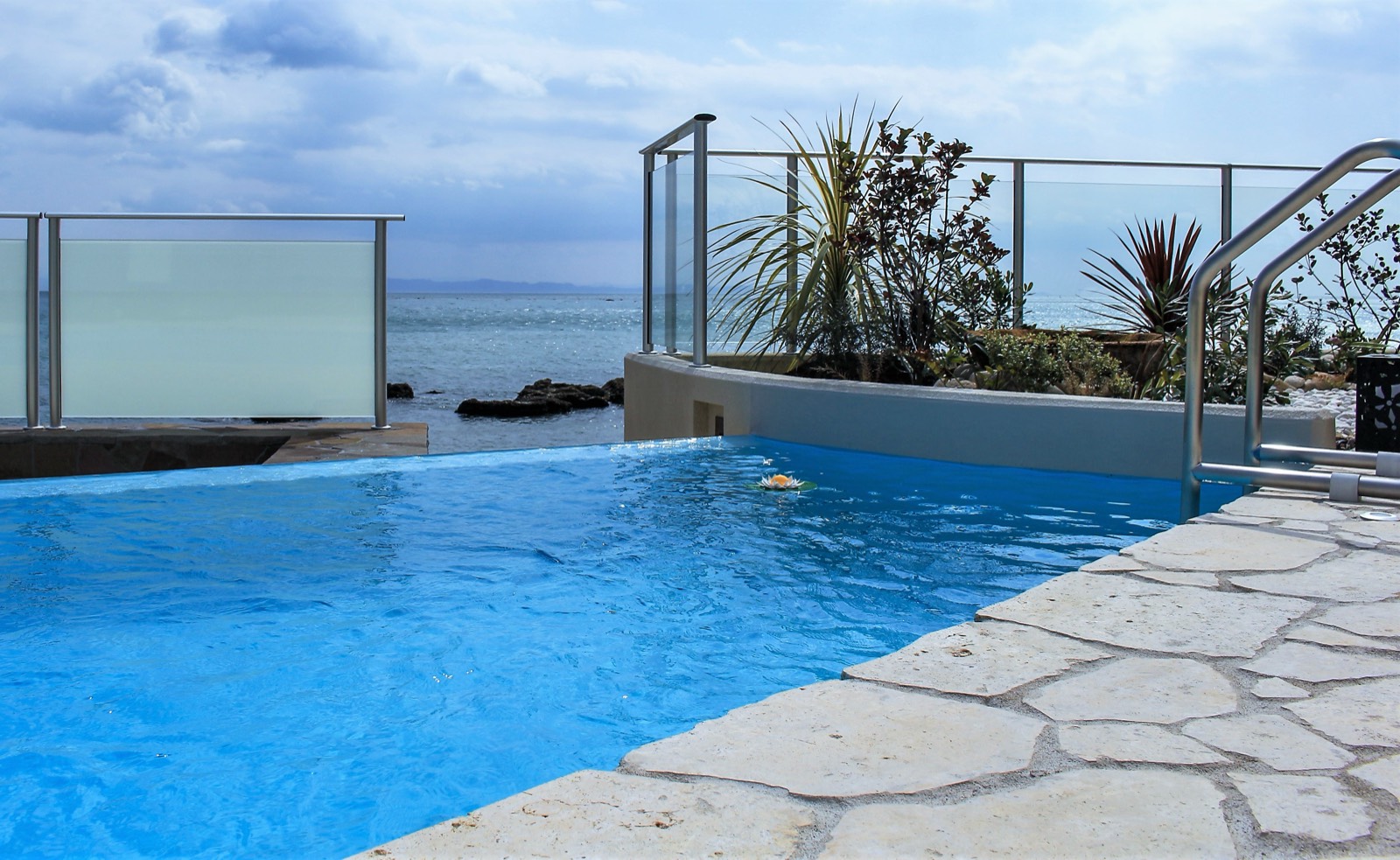 Clear blue pool with stone deck overlooking the water